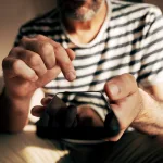 A closeup of a man's holding a smartphone with his finger about to press the screen