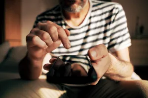 A closeup of a man's holding a smartphone with his finger about to press the screen