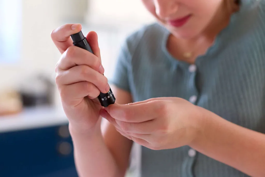 A child using a lancet device to perform a finger-prick blood glucose test